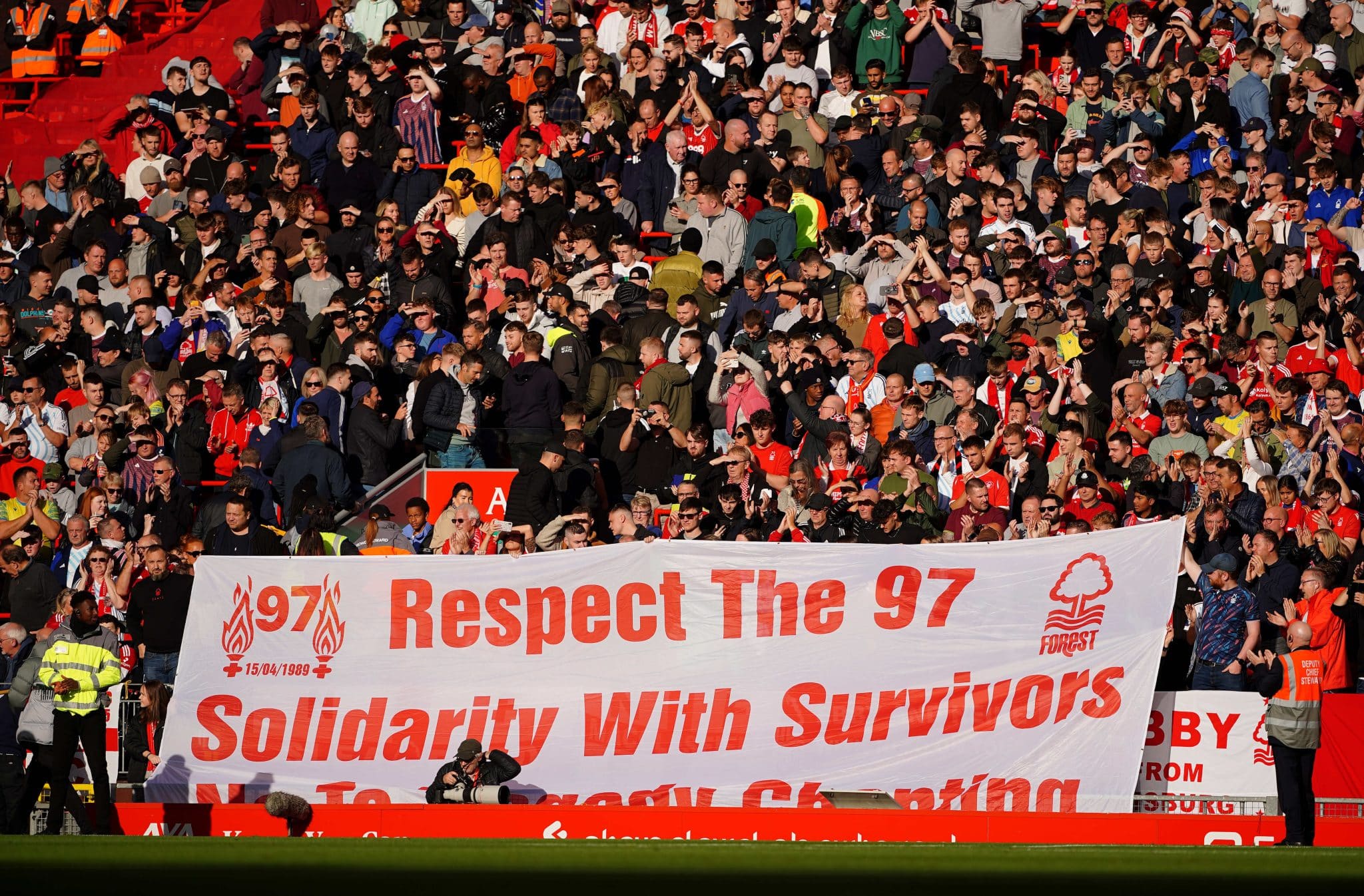 Liverpool fans hold up a banned reading Respect the 97 Solidarity With Survivors You'll Never Walk Alone