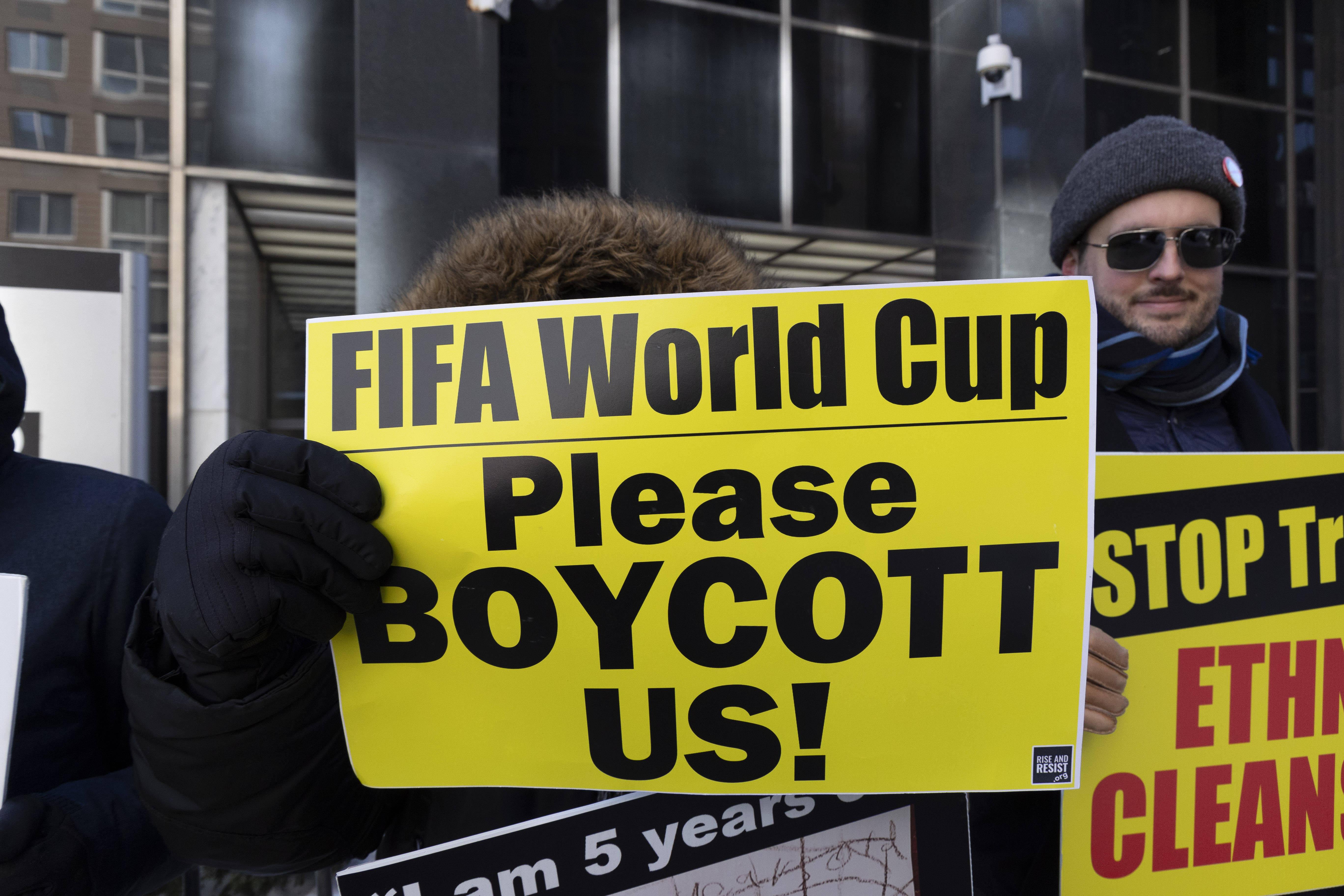 A protester holding a sign that reads 'FIFA World Cup Please BOYCOTT US!'